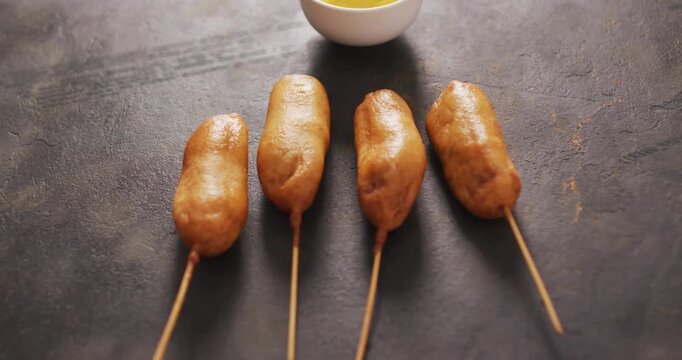 Camera shifting focus from blur to crisp corn dogs and mustard bowl, emphasizing texture in 3D