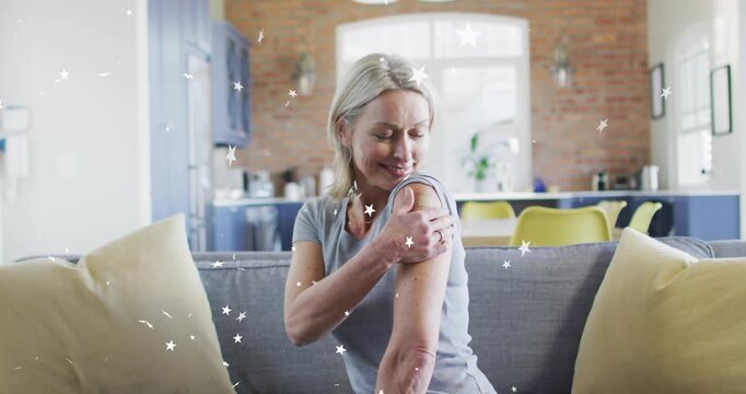 Mature woman spotting bandage and rolling up sleeve inspecting site with health stars glowing