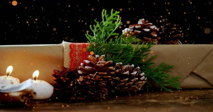 Hand adding candle beside gift and pine cones, sparkles drifting, lighting and removing making glow