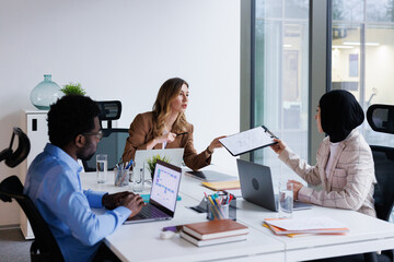 Data analyst in hijab demonstrating chart to boss at staff meeting