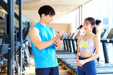 ジムでパーソナルトレーニングの計画について話すトレーナーと女性