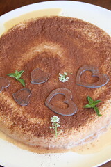 Rich and moist tres leches cake topped with grated chocolate and heart decorations—a festive twist on the classic Latin dessert.