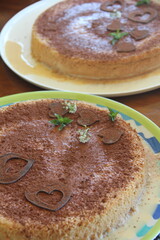 Rich and moist tres leches cake topped with grated chocolate and heart decorations—a festive twist on the classic Latin dessert.