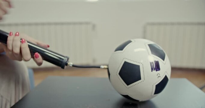 A close-up shot captures hands actively inflating a small soccer ball with a hand pump, then deflating it. The video includes clear and distinct sounds of the inflation and deflation process.