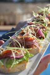 Peruvian-style tapas on crispy baguette with lechón, huacatay and ají sauces, and pickled onions—a bold, flavorful Andean bite.