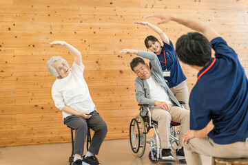 Senior men and women doing exercises and stretching at a nursing home, day care center, and staff