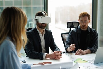 Male company boss wearing VR headset during meeting with architects