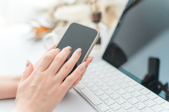 A woman with nails touching the screen of a smartphone