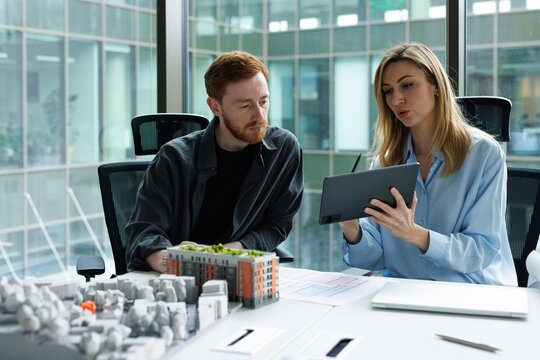 Female architect showing on tablet and telling to male colleague