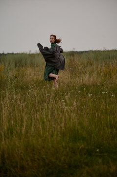 Woman Running Barefoot in Field with Flowing Coat