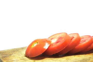 Fresh red tomato slices, solanum lycopersicum or lycopersicum esculentum on an old wooden cutting board photographed on the isolated white background