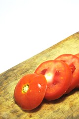 Fresh red tomato slices, solanum lycopersicum or lycopersicum esculentum on an old wooden cutting board photographed on the isolated white background