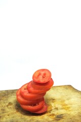 Fresh red tomato slices, solanum lycopersicum or lycopersicum esculentum on an old wooden cutting board photographed on the isolated white background