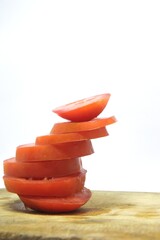 Fresh red tomato slices, solanum lycopersicum or lycopersicum esculentum on an old wooden cutting board photographed on the isolated white background