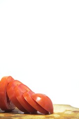 Fresh red tomato slices, solanum lycopersicum or lycopersicum esculentum on an old wooden cutting board photographed on the isolated white background