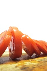 Fresh red tomato slices, solanum lycopersicum or lycopersicum esculentum on an old wooden cutting board photographed on the isolated white background