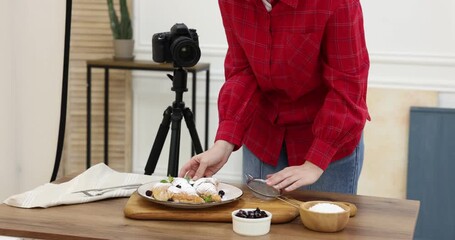 Woman creating composition with croissants at table in studio, closeup. Professional food photography