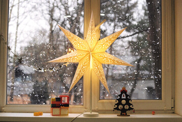 Still life with Christmas light and toy fir-tree at windowsill.