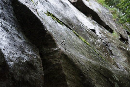 Rain-Soaked Rock Face with climbing fixed bolts outdoors