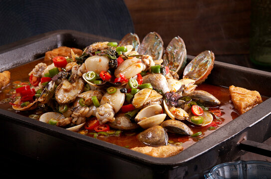 Closeup of spicy braised clams, abalone, and baby cuttlefish in a wok