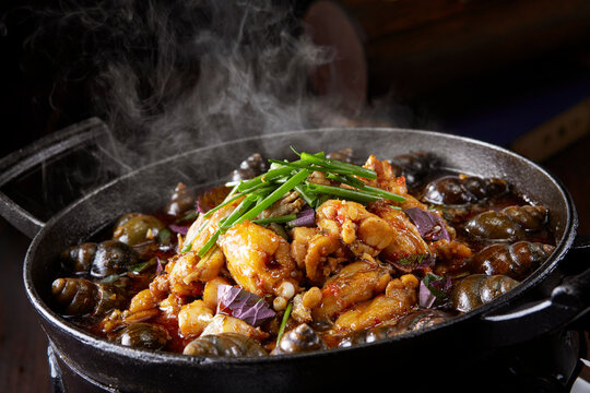 Wok-fried frog meat with perilla and field snails, close-up