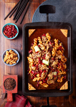 Spicy braised frog meat in a wok with twisted dough sticks
