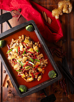 Spicy braised frog meat in a wok with ginger slices.