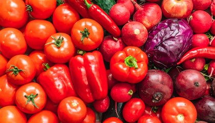 Vibrant red vegetables flat lay background. Fresh organic mix of tomatoes, bell peppers, radishes, onions, and red cabbage for healthy diet and cooking concepts.