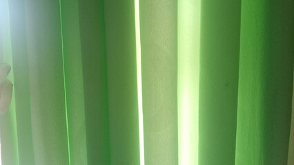 A bright green curtain texture with folds and natural light effects. This image features an abstract and minimalist gradient background, perfect for designs that require a fresh feel.