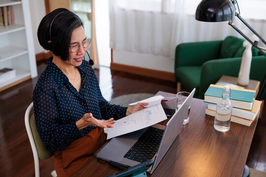 Woman presenting data during a video call at home.