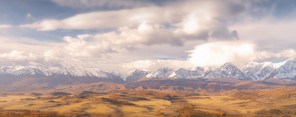 Stunning view of the Altai mountains showcases vibrant autumn colors with golden valleys contrasting against snow-capped peaks. The scene reflects nature beauty and tranquility.