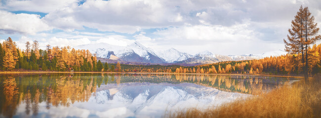 Kidel Lake reflects the beauty of the Altai Mountains, framed by vibrant autumn foliage. A serene landscape showcases natures colors and tranquility in a breathtaking setting.