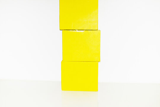 Pile of yellow empty mockup cardboard boxes with space for text/design