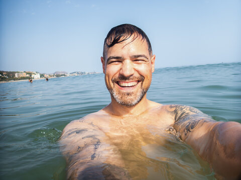 Happy man taking a selfie while swimming in the sea