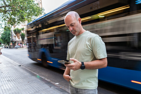 Man using smartphone while bus passing by in the city