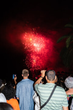 Crowd watching amazing red fireworks exploding in the night sky