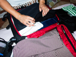 Woman packing clothes in suitcase for travel, preparing