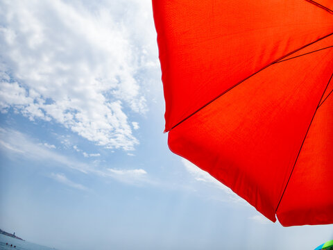 Orange parasol providing shade on a sunny day at the beach