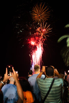 Crowd enjoying and recording fireworks display with smartphones