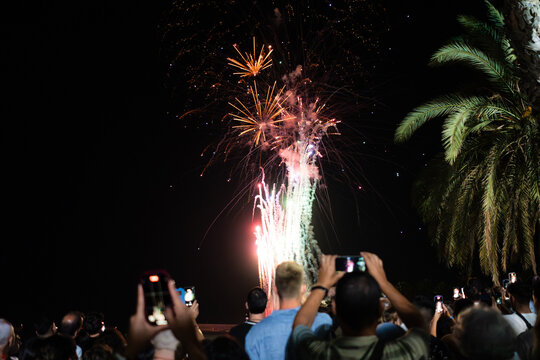 Crowd filming colorful fireworks exploding in the night sky