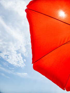 Orange parasol covering the sun in a cloudy sky