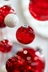 Red and white glass Christmas baubles hanging in vertical composition