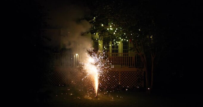 Backyard Fireworks at Night with Cozy String Lights &ndash; Warm Family Celebration Vibes in Suburban Garden with Sparkling Fountains and Smoke. Holiday or Special Event at Home.