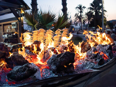 Espetos de sardinas grilling over hot coals in Malaga, Spain