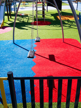Empty swings hanging in playground on sunny day