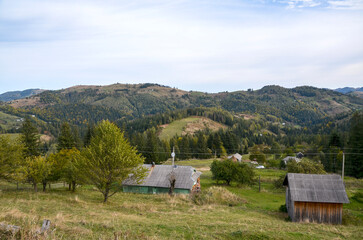 Tranquil rural landscape with small village tucked into rolling hills dense forests and scattered cottages Sunlit scene featuring winding road and distant mountains conveying calm and countryside life