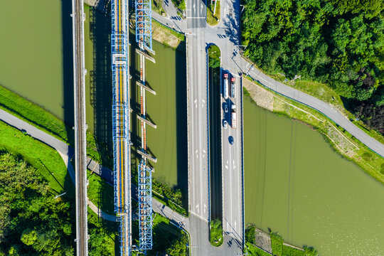 Road bridge with vehicles and industrial pipelines crossing river
