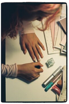 A young girl does her nails instead of doing her homework.
