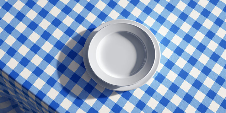 White plate on blue and white checkered tablecloth viewed from above, creating simple and clean aesthetic. pattern adds classic touch to dining setup