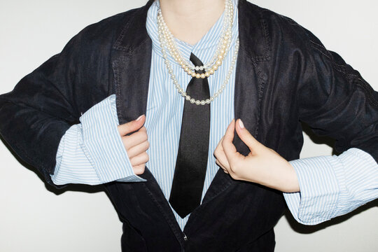 Person wearing suit, tie and shiny pearl necklaces in business office